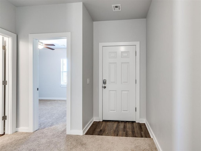 interior space featuring ceiling fan, visible vents, baseboards, and dark colored carpet