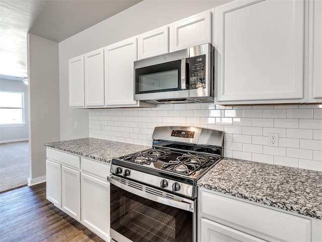 kitchen featuring light stone counters, stainless steel appliances, baseboards, white cabinetry, and decorative backsplash