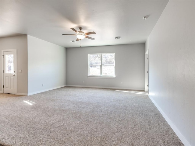 unfurnished room with light colored carpet, baseboards, ceiling fan, and visible vents