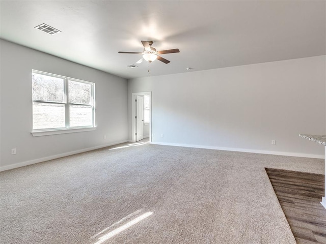 spare room with carpet flooring, a ceiling fan, baseboards, and visible vents
