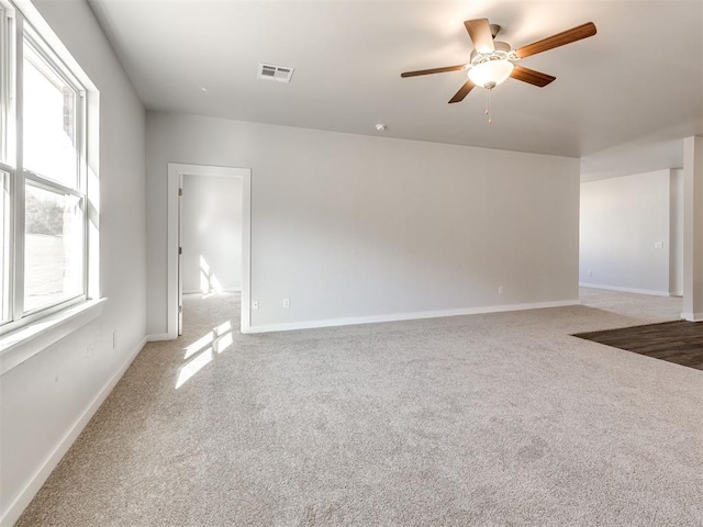 carpeted empty room with visible vents, baseboards, and ceiling fan