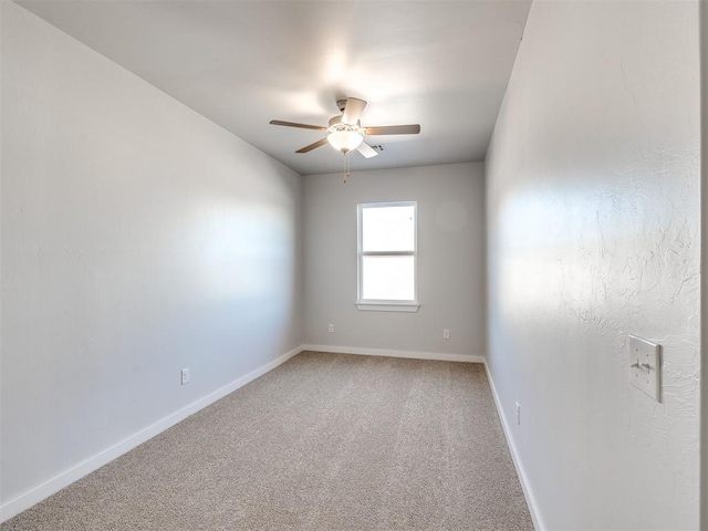 spare room with light colored carpet, baseboards, and ceiling fan
