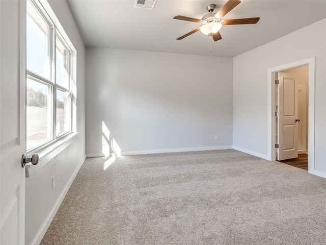 empty room with baseboards, a ceiling fan, carpet, and visible vents