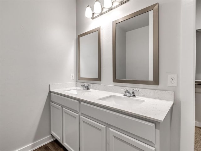bathroom with a sink, baseboards, and double vanity