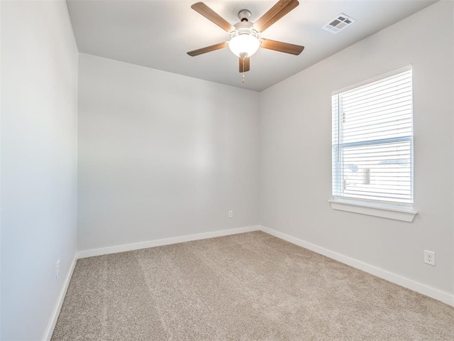 carpeted empty room with baseboards, ceiling fan, and visible vents