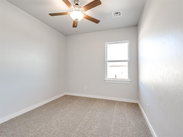 carpeted spare room featuring ceiling fan, visible vents, and baseboards