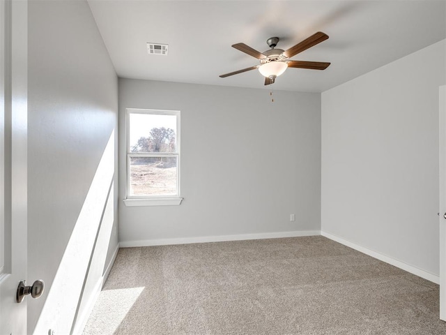 carpeted spare room with baseboards, ceiling fan, and visible vents