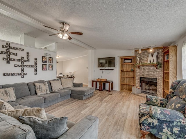 living room with ceiling fan, track lighting, a fireplace, a textured ceiling, and wood finished floors