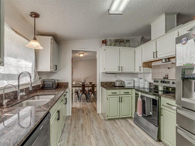kitchen featuring a textured ceiling, a sink, light wood-style flooring, appliances with stainless steel finishes, and green cabinets
