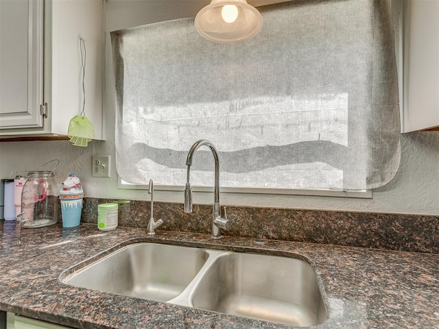 interior details featuring a sink and dark stone countertops