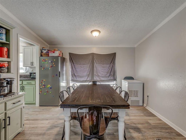 dining space featuring a textured ceiling, ornamental molding, and light wood-style floors