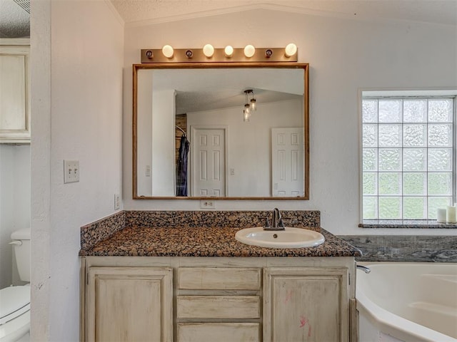 bathroom featuring a garden tub, a textured ceiling, crown molding, vanity, and toilet