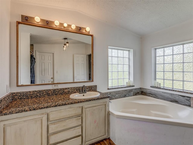 bathroom featuring vanity, a bath, a textured ceiling, and lofted ceiling
