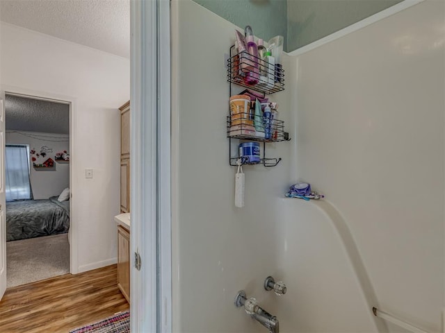full bathroom with vanity, a textured ceiling, wood finished floors, and a tub
