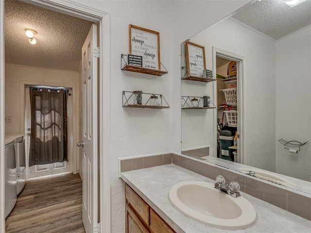 bathroom featuring separate washer and dryer, a textured ceiling, wood finished floors, and vanity