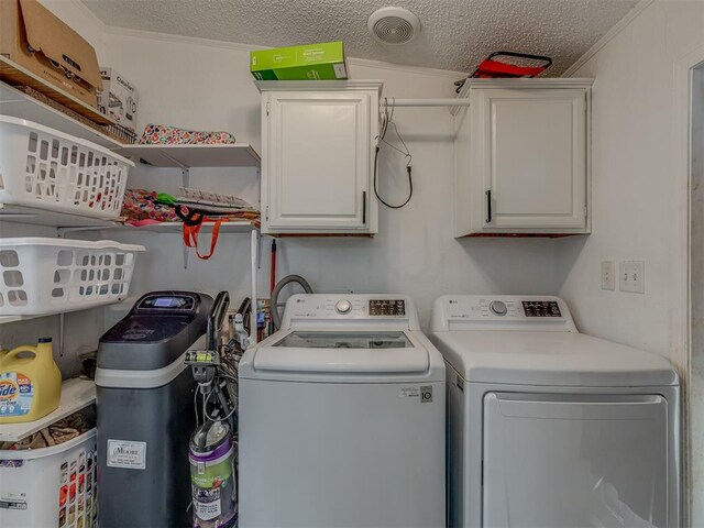 washroom featuring cabinet space, a textured ceiling, washing machine and dryer, and ornamental molding