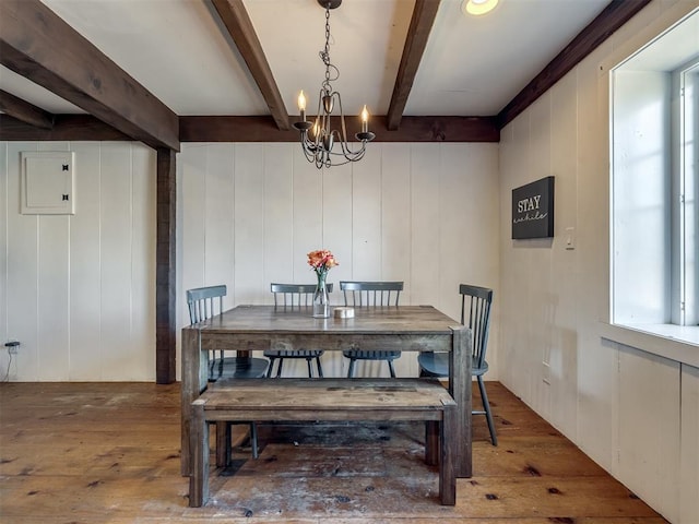 dining area featuring wood-type flooring, plenty of natural light, beam ceiling, and an inviting chandelier