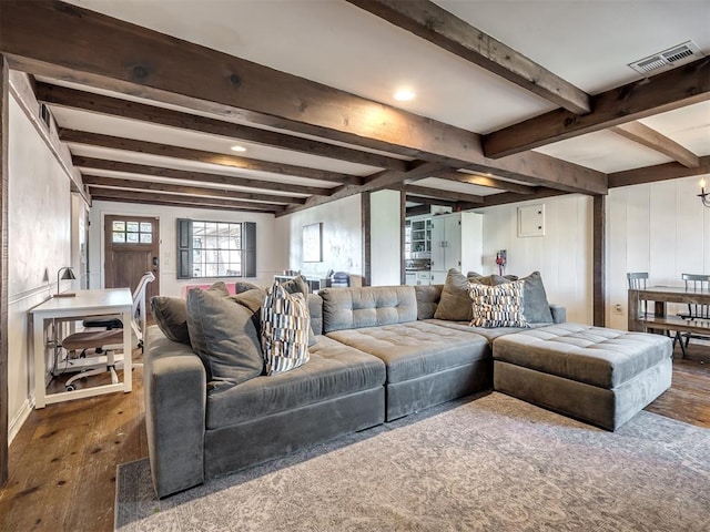 living area featuring hardwood / wood-style flooring, beam ceiling, and visible vents