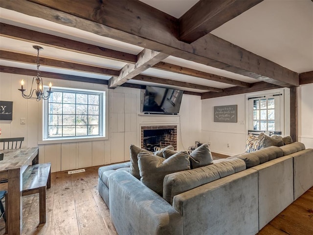 living area with visible vents, wood-type flooring, beam ceiling, and a notable chandelier