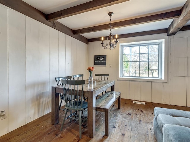 dining room with an inviting chandelier, beamed ceiling, hardwood / wood-style flooring, and visible vents