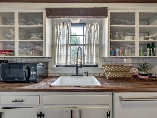 bar with black microwave, backsplash, a sink, and dishwasher
