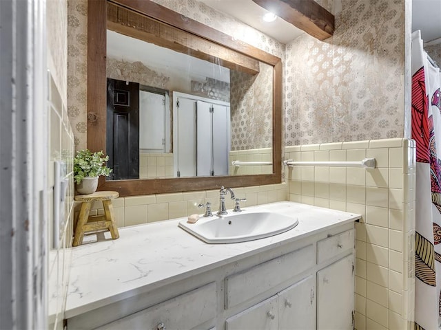 full bath featuring vanity, a wainscoted wall, wallpapered walls, and tile walls