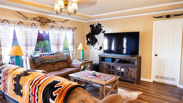 living area with a notable chandelier, baseboards, wood finished floors, visible vents, and ornamental molding