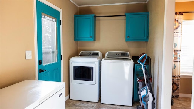 laundry area featuring baseboards, washer and clothes dryer, cabinet space, and ornamental molding