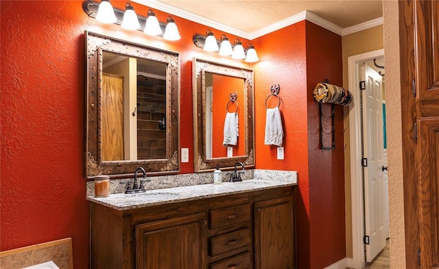 full bath with a sink, a textured wall, and ornamental molding