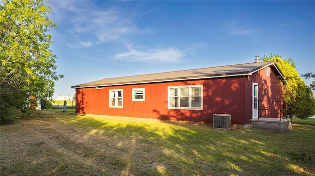 rear view of house featuring a lawn, central AC unit, and metal roof