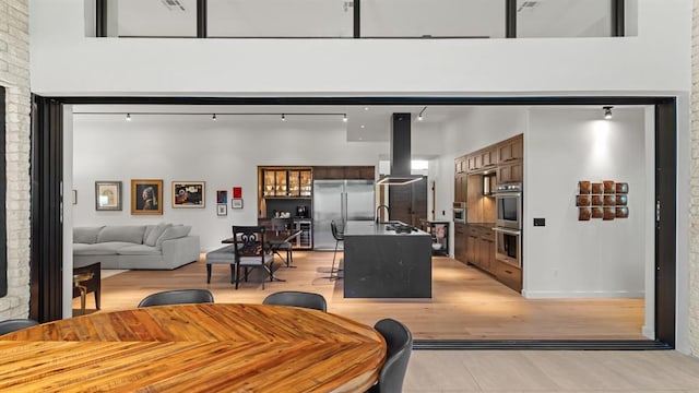 dining space featuring a towering ceiling and light wood-type flooring