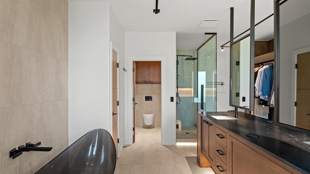 full bathroom featuring a stall shower, tile walls, double vanity, a bath, and toilet