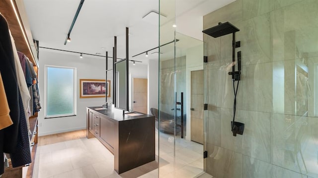bathroom with a shower stall, vanity, and rail lighting