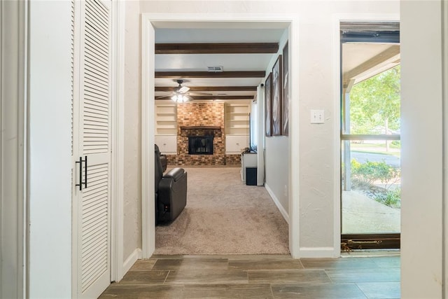 hall featuring wood finished floors, baseboards, beam ceiling, and visible vents