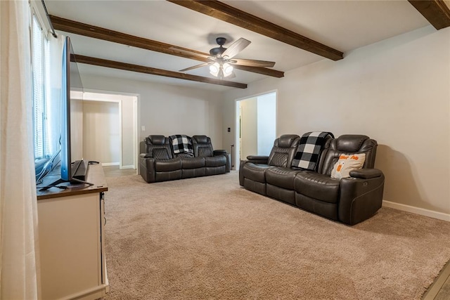 living area featuring baseboards, a ceiling fan, carpet, and beamed ceiling