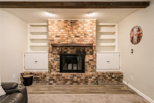 living room with baseboards, built in features, wood finished floors, and a fireplace
