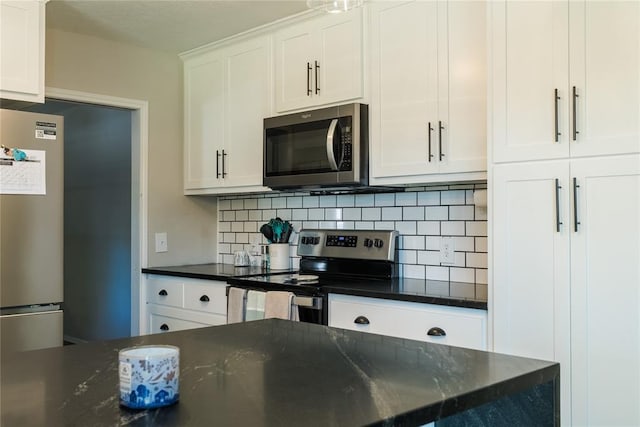 kitchen featuring white cabinets, dark stone countertops, tasteful backsplash, and stainless steel appliances