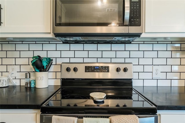 kitchen featuring stainless steel appliances, dark countertops, white cabinetry, and tasteful backsplash