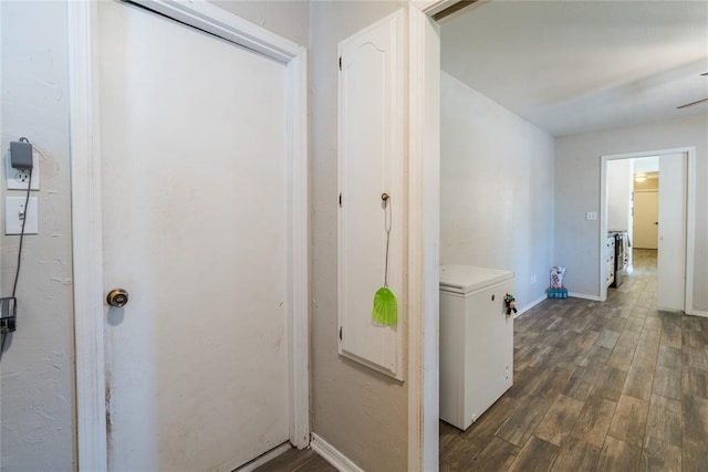 corridor featuring baseboards and dark wood-style flooring
