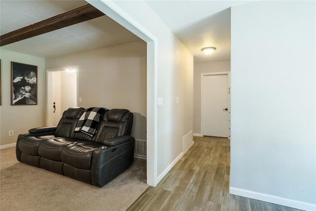 corridor featuring baseboards, visible vents, wood finished floors, and beam ceiling