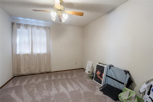 carpeted spare room featuring baseboards and a ceiling fan