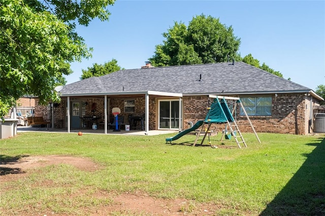 rear view of house with a lawn, brick siding, and a playground
