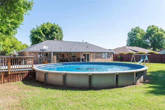 view of pool featuring a deck, a fenced backyard, a fenced in pool, a playground, and a lawn