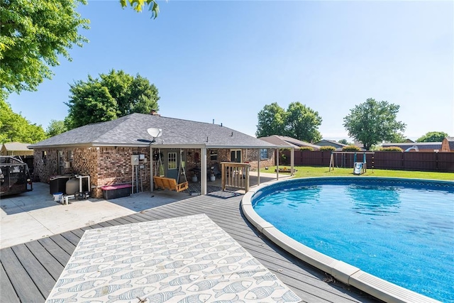 view of swimming pool with a wooden deck, a fenced backyard, a fenced in pool, a lawn, and a patio