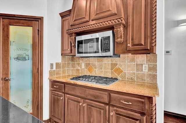 kitchen featuring dark wood-type flooring, decorative backsplash, appliances with stainless steel finishes, and light stone countertops