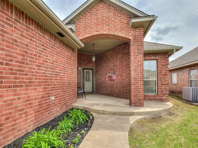 entrance to property with central air condition unit and brick siding