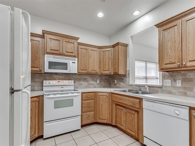 kitchen with a sink, white appliances, light countertops, and tasteful backsplash