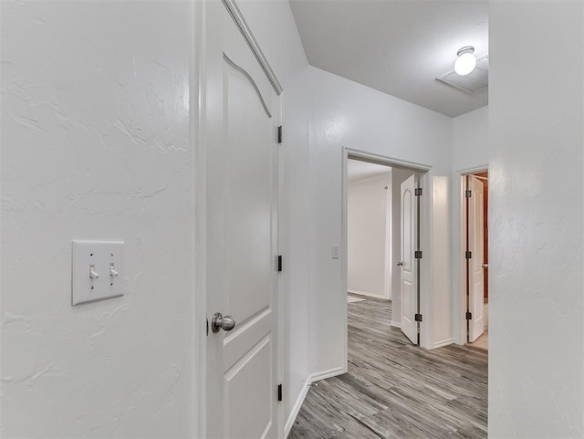 corridor featuring wood finished floors and baseboards