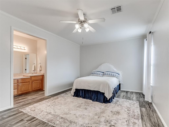 bedroom featuring baseboards, ensuite bathroom, ornamental molding, visible vents, and wood finished floors