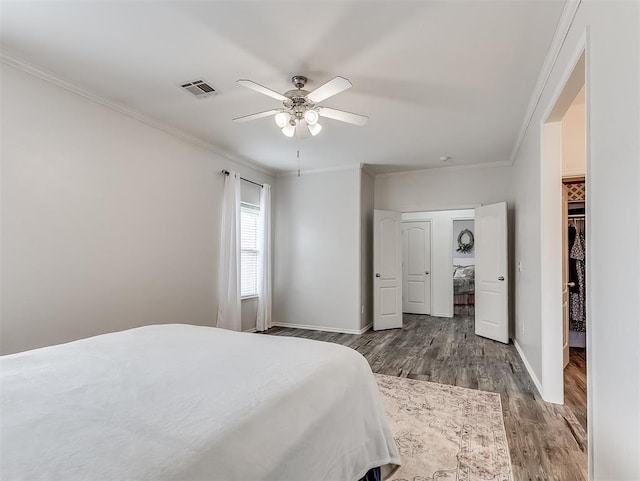 bedroom featuring baseboards, ornamental molding, visible vents, and wood finished floors